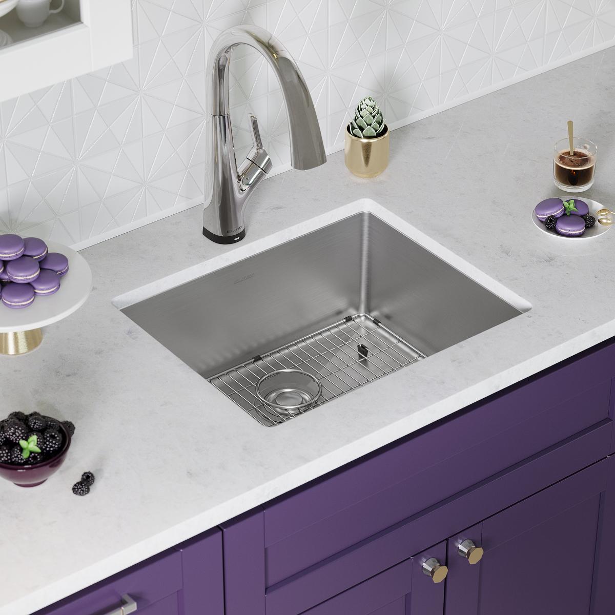 Stainless steel single bowl undermount sink with pull-down faucet and grid strainer installed in white countertop.