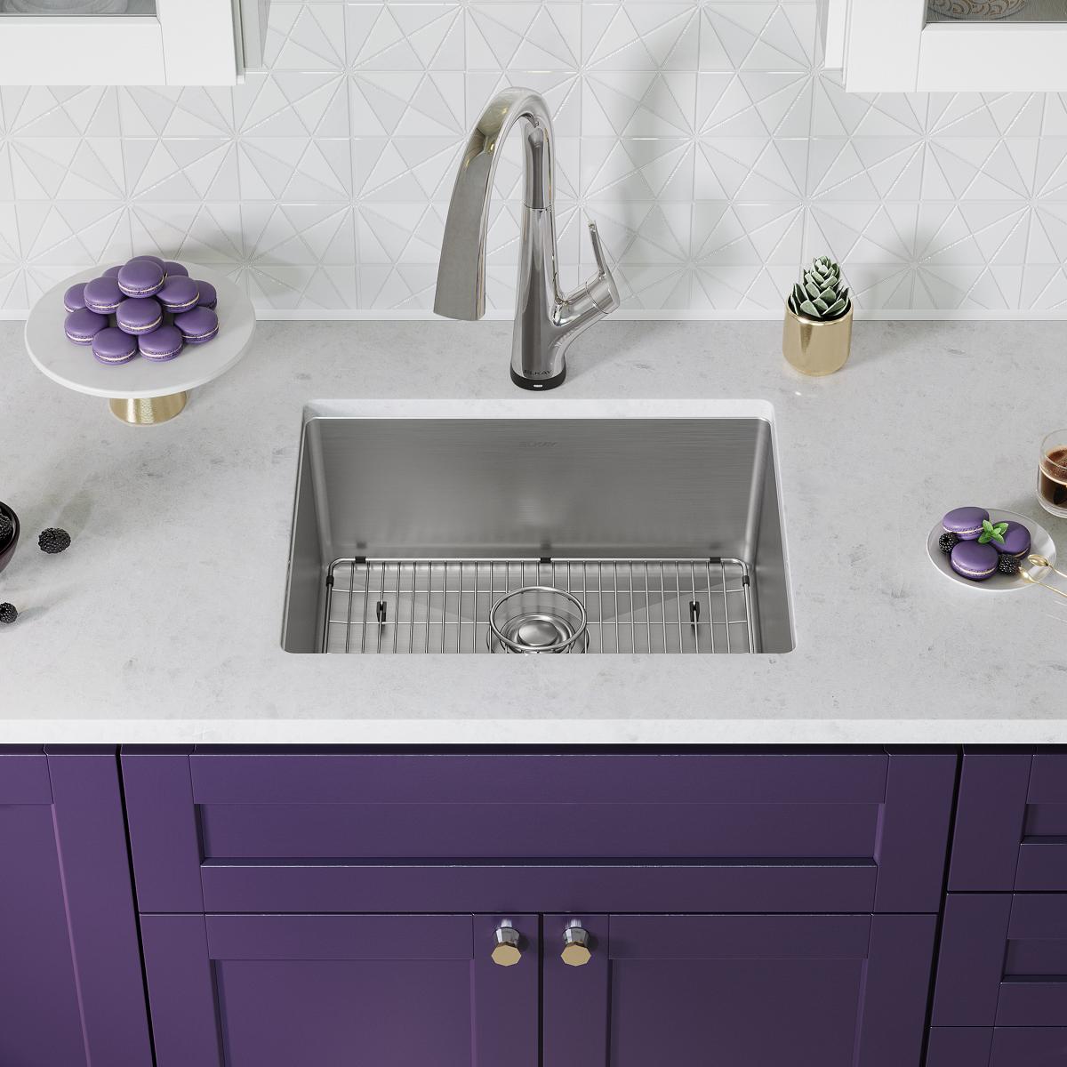 Stainless steel undermount sink with single bowl, grid rack, and chrome filtered faucet installed in white countertop above p