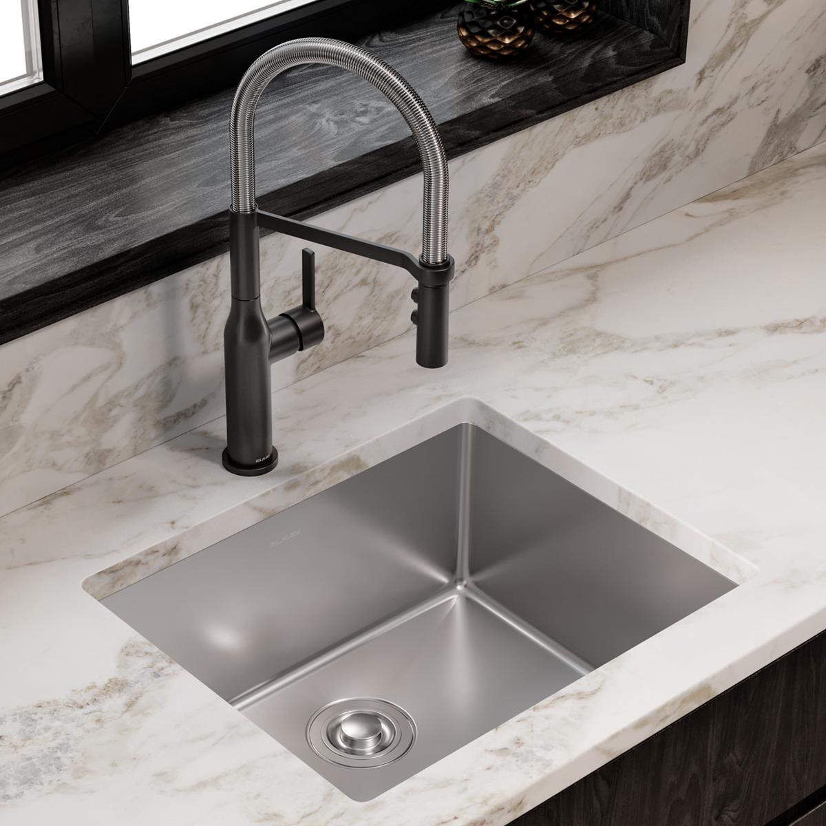 Stainless steel single bowl undermount sink installed in marble countertop with black pull-down faucet.