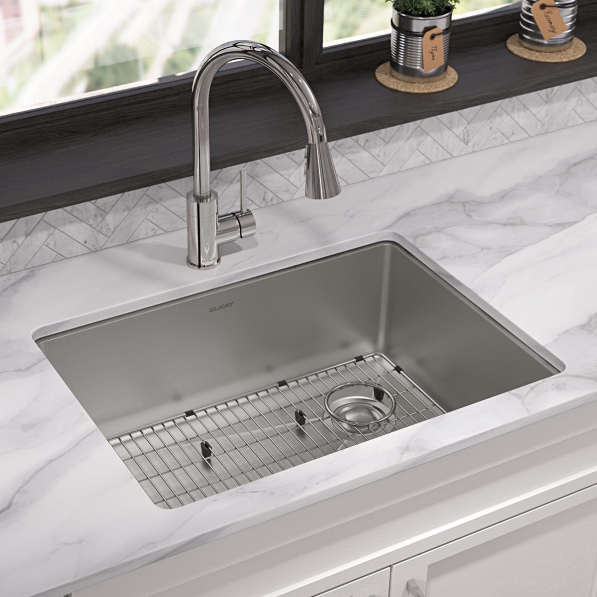 Stainless steel undermount sink with single bowl, bottom grid, drain, and chrome pull-down faucet installed in marble counter