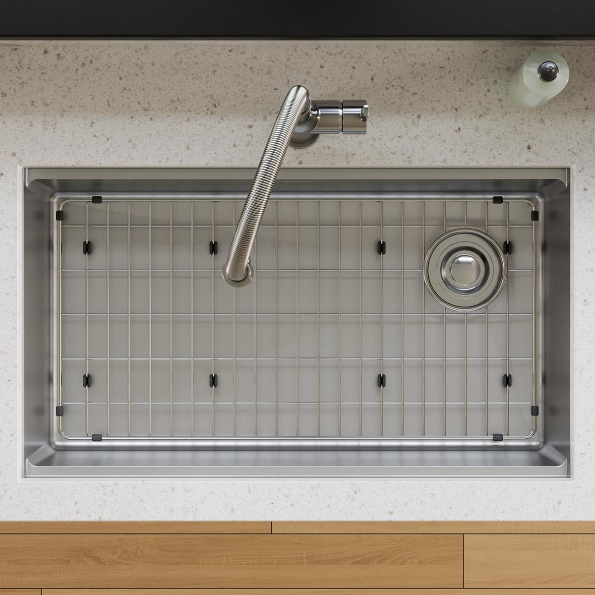 Stainless steel sink grid with rectangular wire pattern and corner feet, designed to fit sink basin.