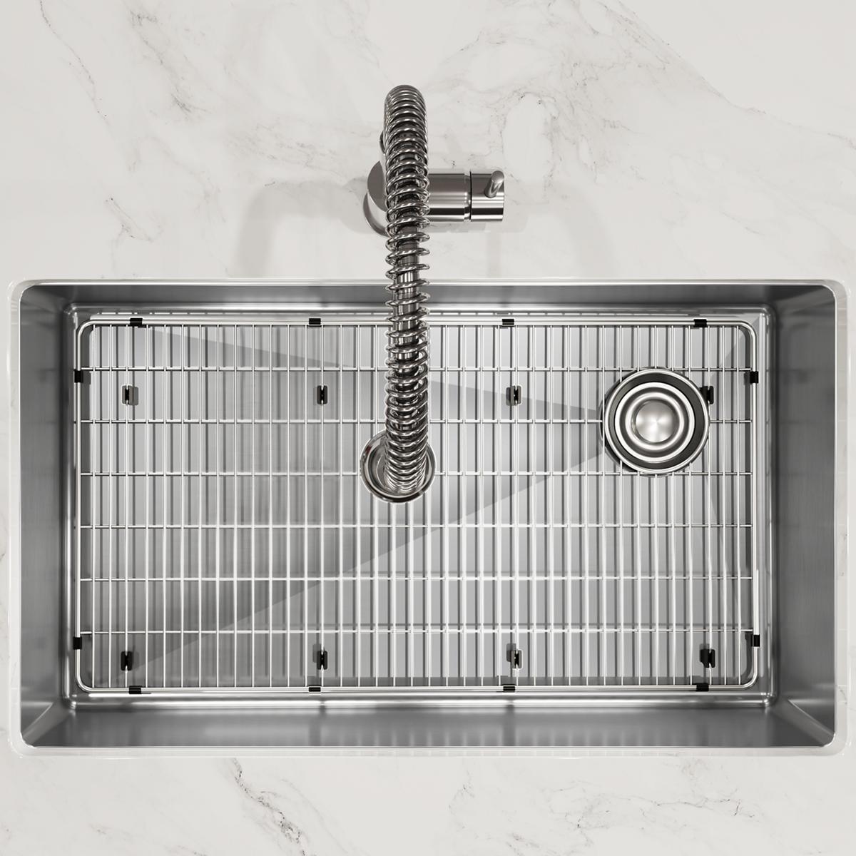 Stainless steel undermount sink with single bowl, grid insert, sprayer faucet, and drain strainer, overhead view.