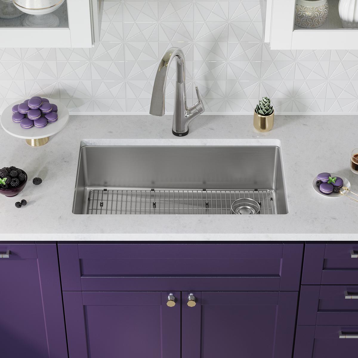 Stainless steel undermount sink with single bowl, grid insert, and chrome filtered faucet installed in white countertop above