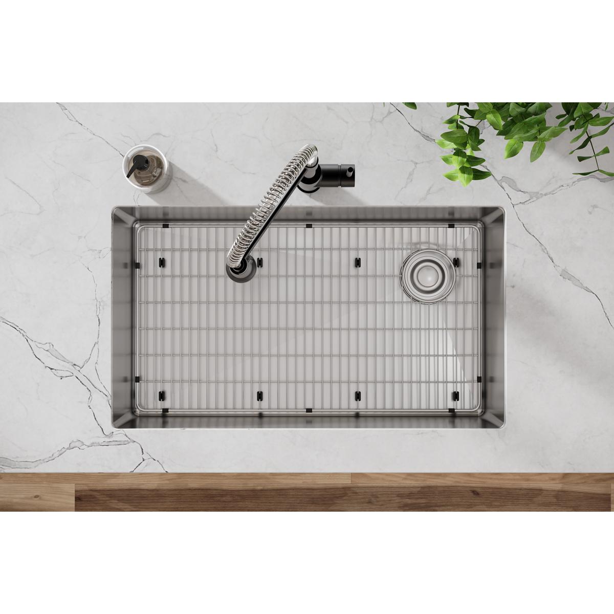 Stainless steel sink grid with parallel slat pattern and rubber feet, shown installed in undermount sink basin.