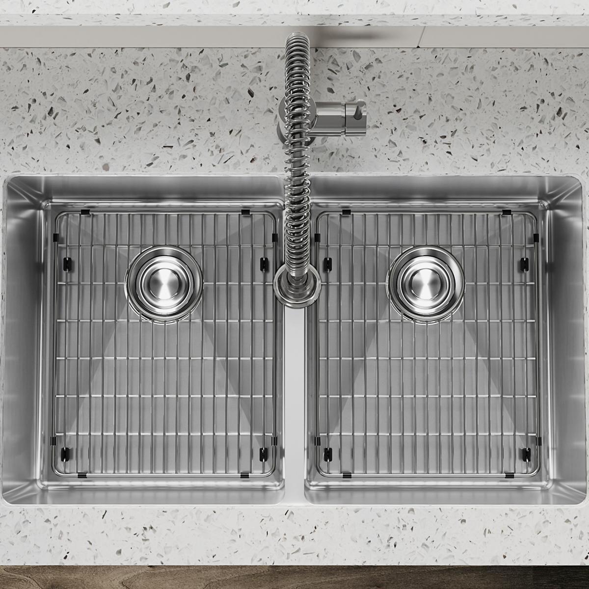 Stainless steel double bowl undermount sink with two equal basins, grid inserts, and spiral faucet mounted on speckled counte