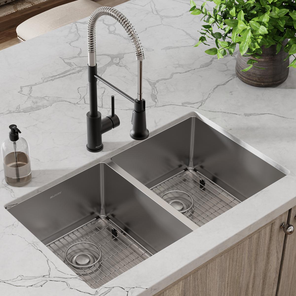 Stainless steel double bowl undermount sink with black pull-down faucet, grid inserts, and drain strainers installed in marbl