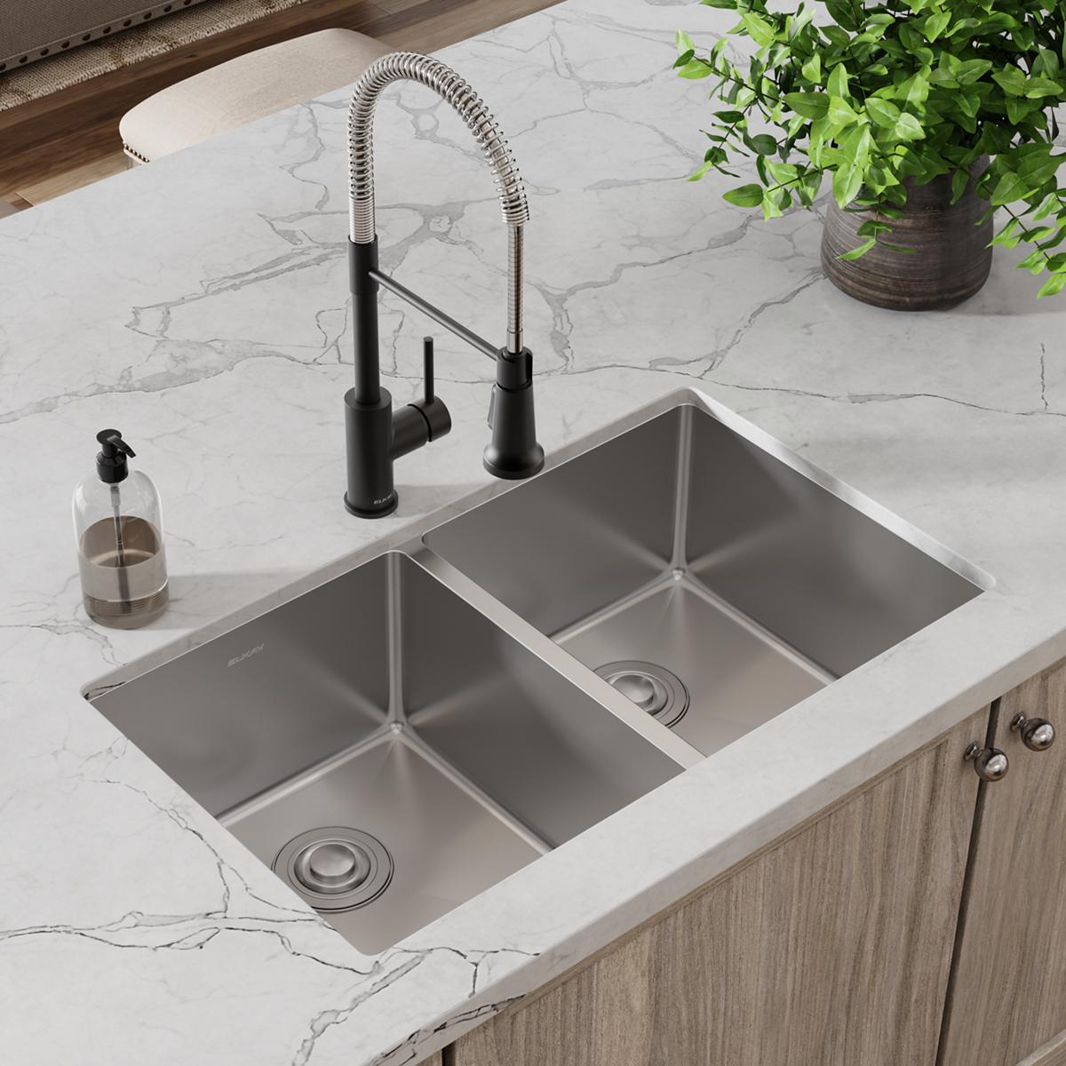 Stainless steel double bowl undermount sink with black pull-down faucet installed in white marble countertop.