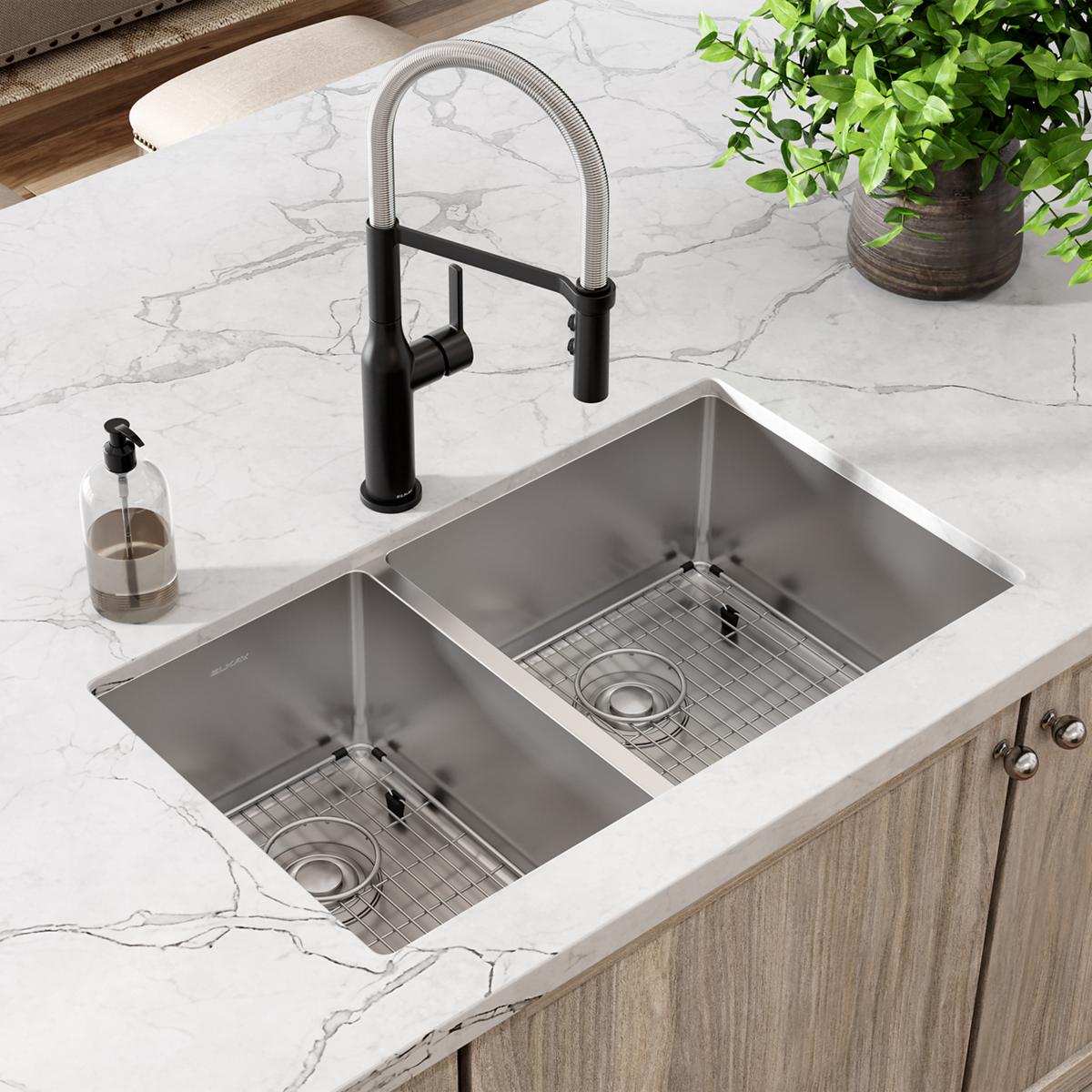 Stainless steel double bowl undermount sink with black pull-down faucet installed in marble countertop above wooden cabinets.