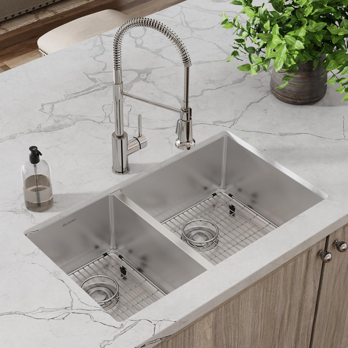 Stainless steel double bowl undermount sink with two grids and drains, paired with a pull-down spray faucet on marble counter