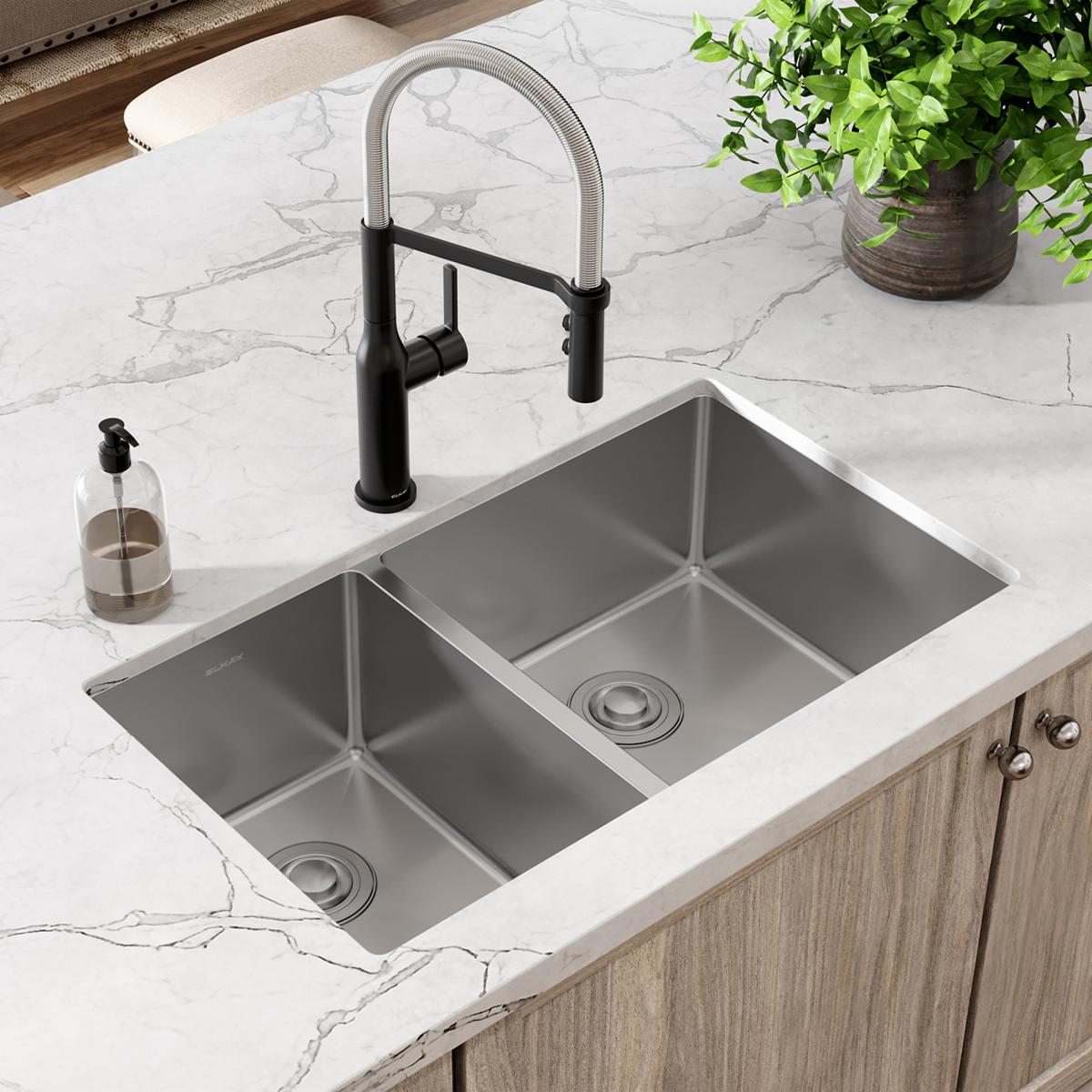 Stainless steel double bowl undermount sink with black pull-down faucet installed in marble countertop.