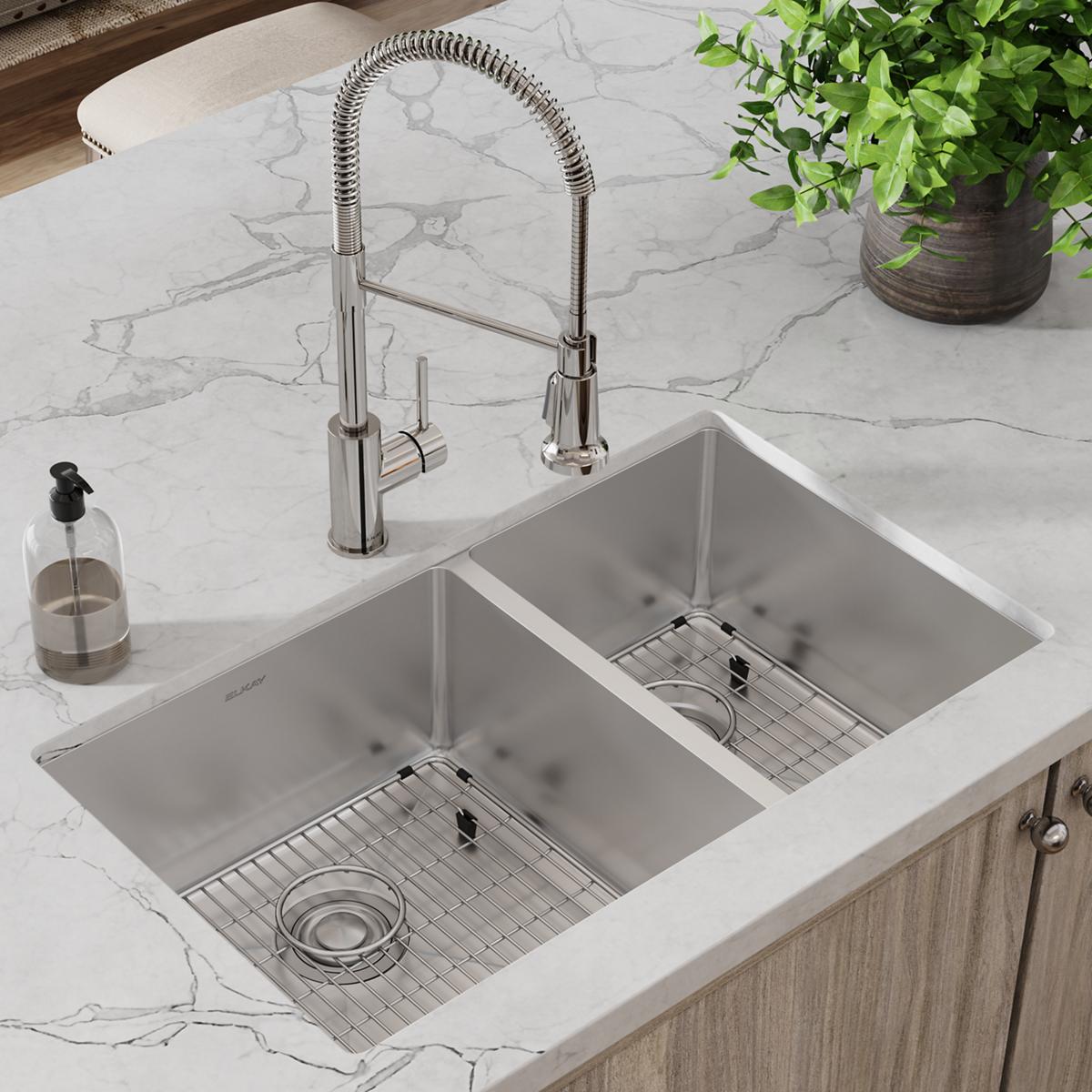 Stainless steel undermount double bowl sink with two pull-down faucets and bottom grids installed in marble countertop.