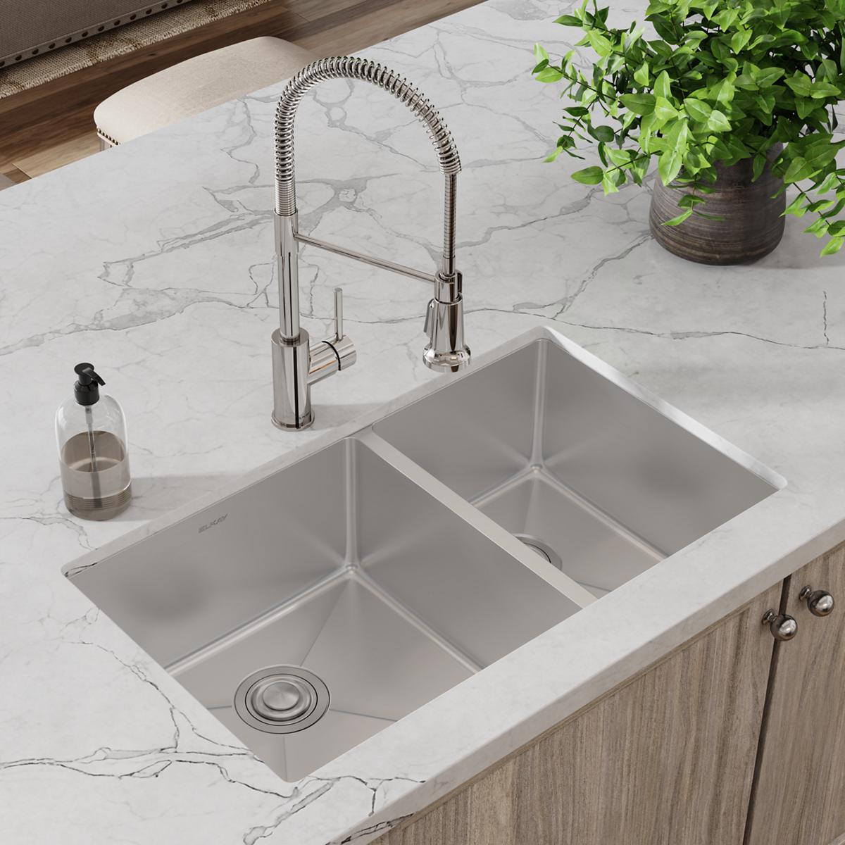 Stainless steel double bowl undermount sink with pull-down faucet installed in marble countertop.