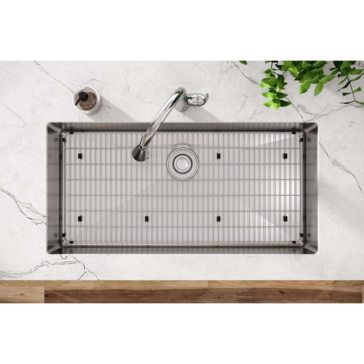 Stainless steel single-bowl undermount sink with grid and drain strainer, viewed from above on marble countertop.