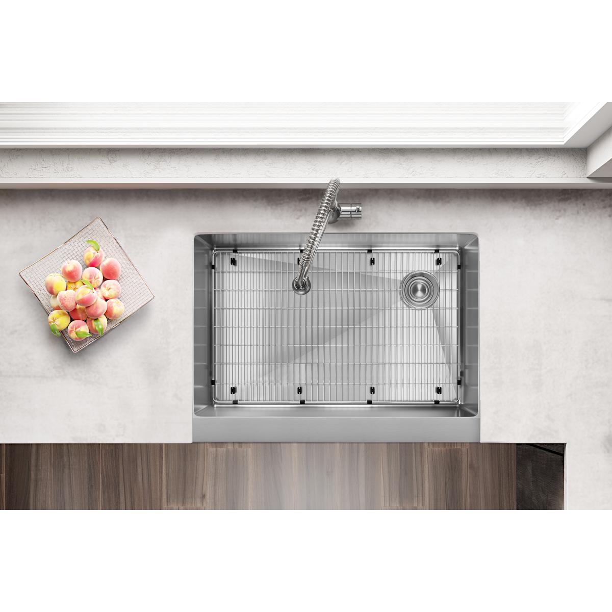 Stainless steel single bowl farmhouse sink with grid insert and spiral faucet, viewed from above on light countertop.