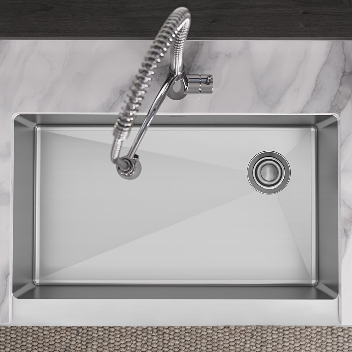 Stainless steel single bowl farmhouse sink with curved edges, drain hole, and flexible spray faucet, viewed from above.