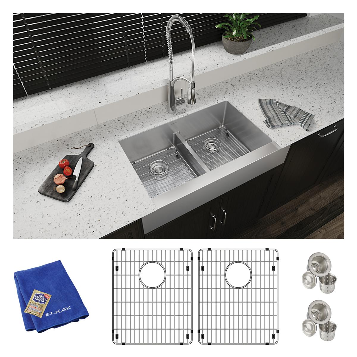 Stainless steel double bowl farmhouse sink installed with faucet, including grid inserts, strainers, and blue cloth.