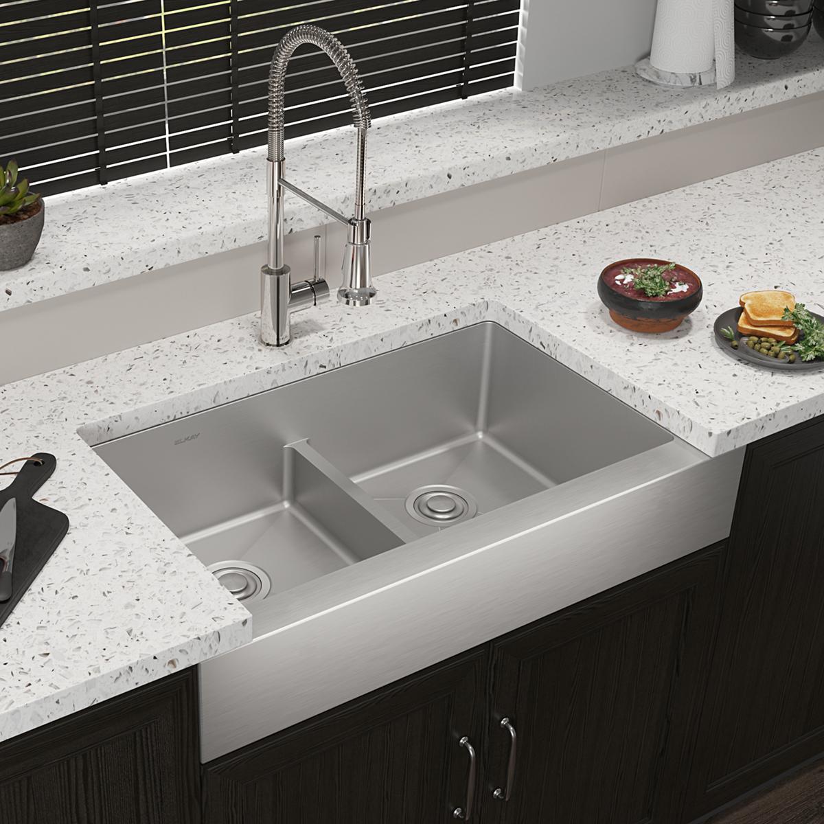 Stainless steel double bowl farmhouse sink with chrome pull-down faucet installed in speckled white countertop.
