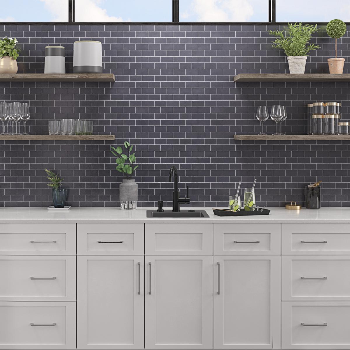 Stainless steel single bowl bar sink with black faucet mounted in white cabinet with dark subway tile backsplash and wooden s