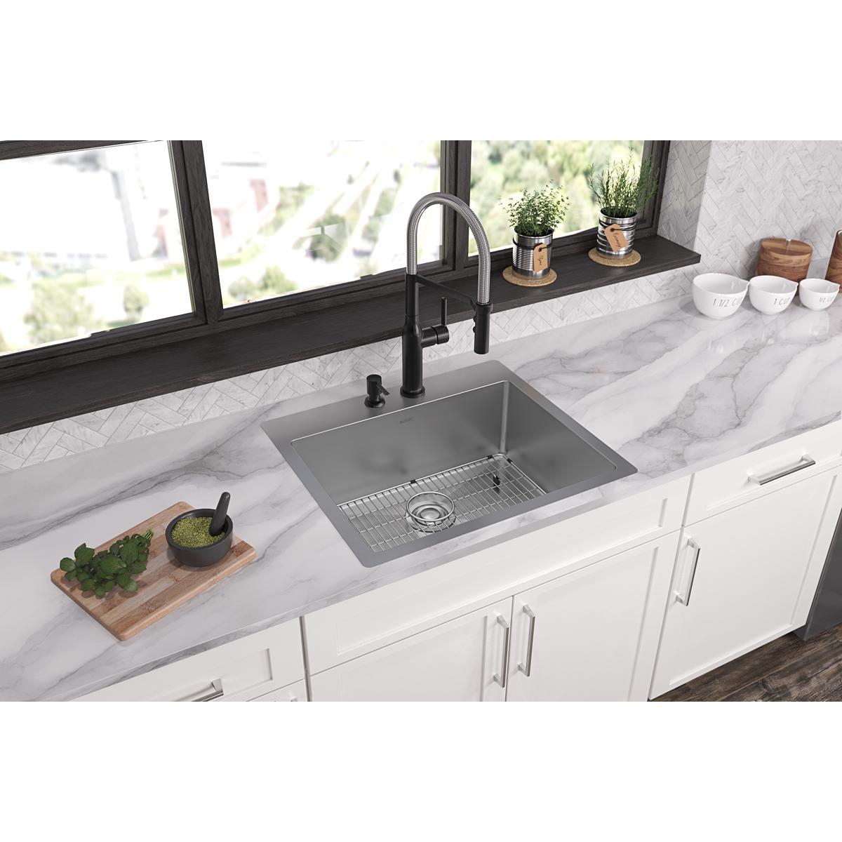 Stainless steel single bowl sink with two faucet holes installed in white kitchen countertop with black faucet and grid strai