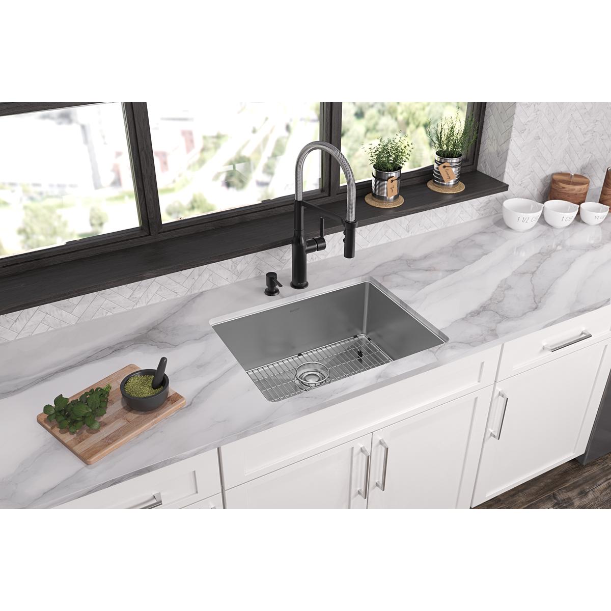Stainless steel single bowl sink with grid installed in white kitchen countertop, paired with black faucet.