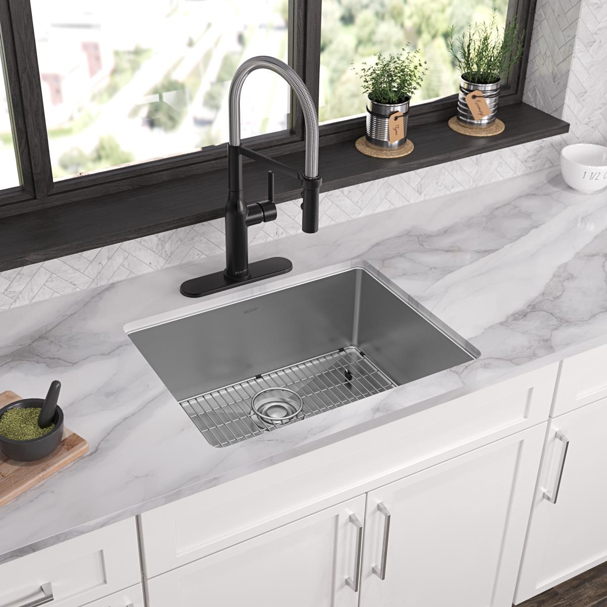 Stainless steel single bowl sink with 3 faucet holes, wire grid insert, and black pull-down faucet installed in marble counte