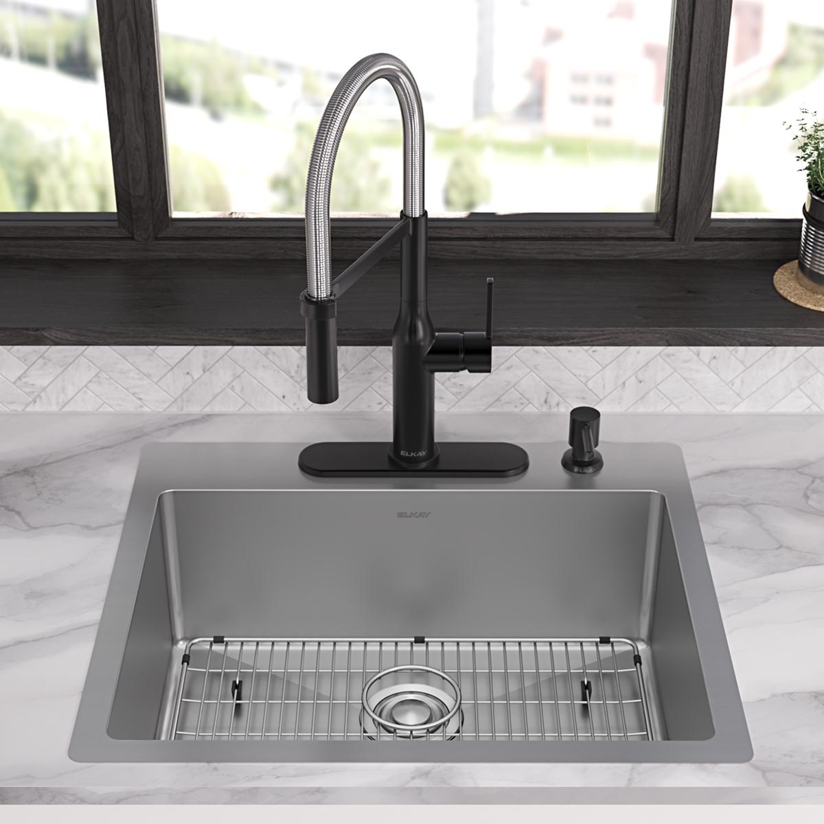 Stainless steel single bowl sink with pull-down faucet, drain basket, and black faucet base installed in marble countertop.