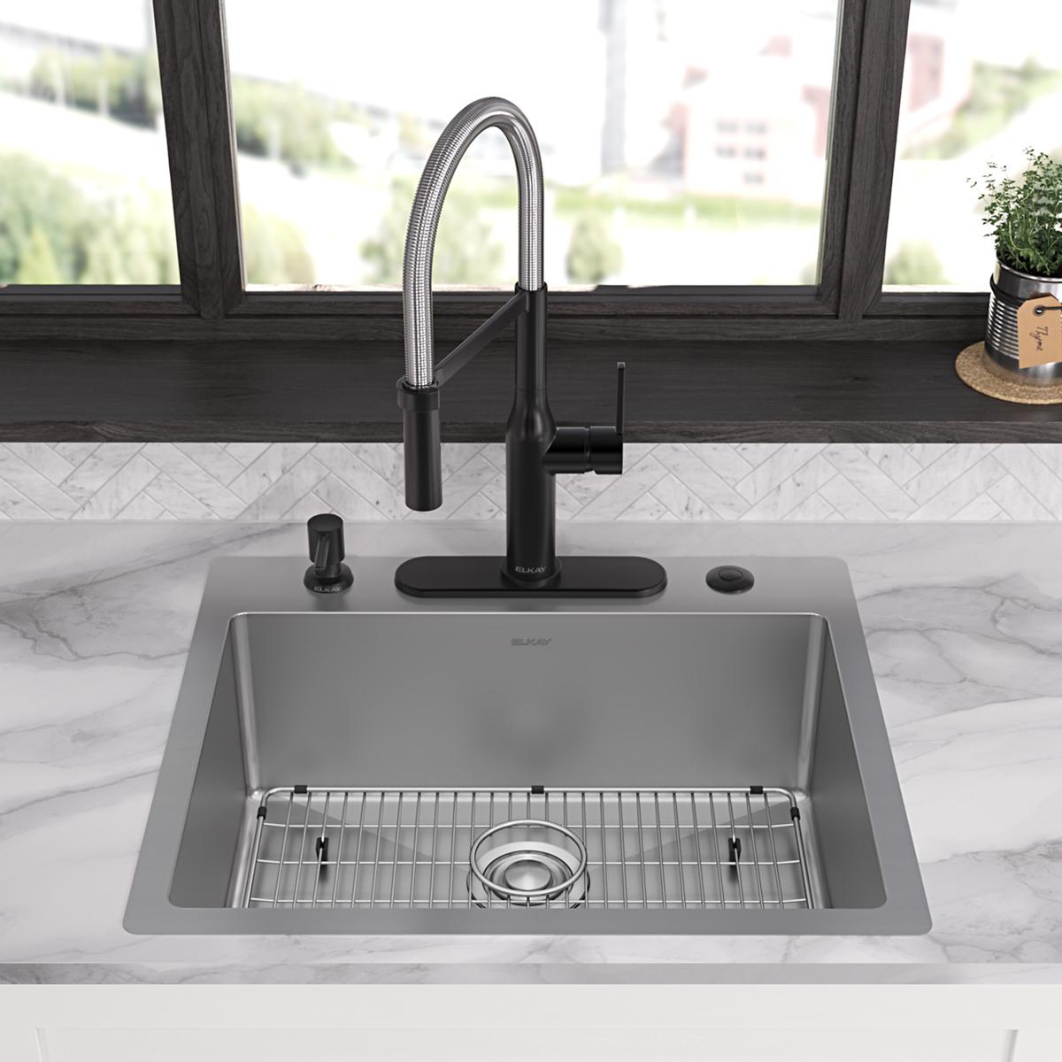 Stainless steel single bowl kitchen sink with black pull-down faucet, grid insert, and mounting accessories on marble counter