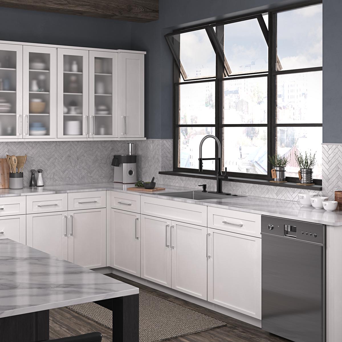 Stainless steel single bowl sink with black pull-down faucet installed in white kitchen cabinetry with marble countertop.