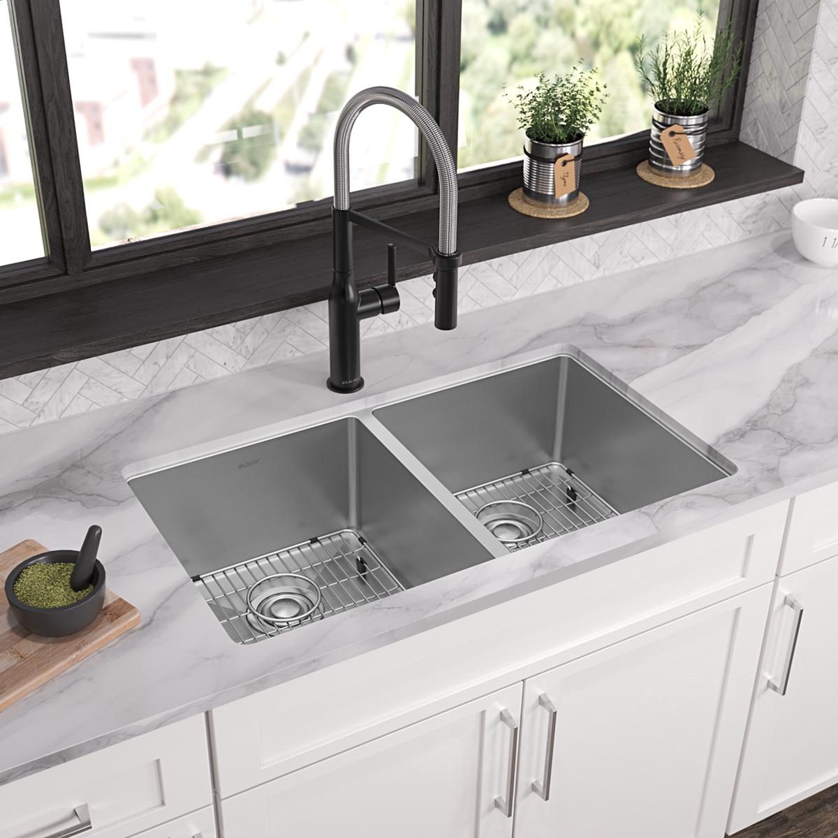Stainless steel double bowl sink with equal-sized basins, metal grid inserts, and black pull-down faucet installed in marble 