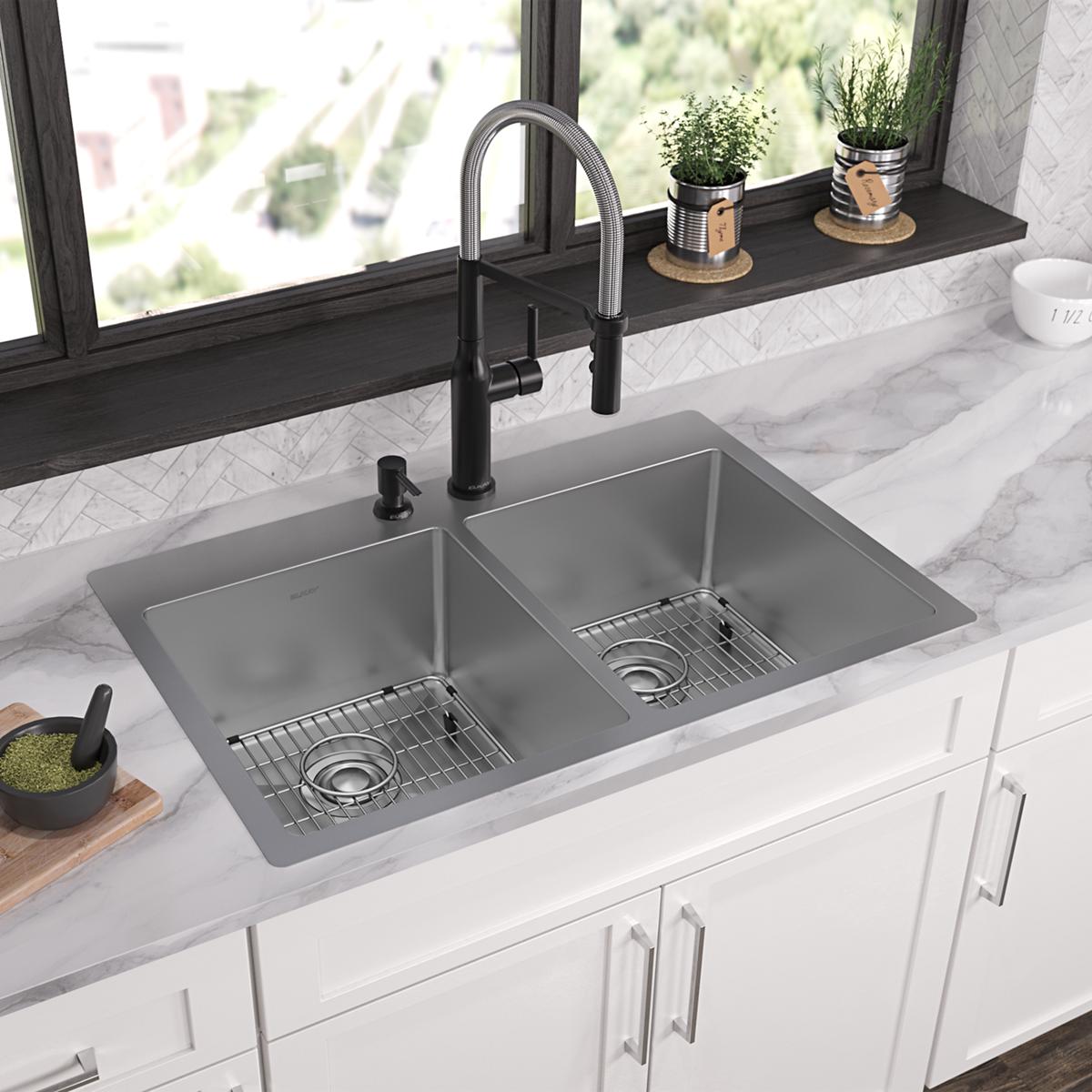 Stainless steel double bowl sink with two equal rectangular basins, each with grid insert and drain hole, mounted in white co
