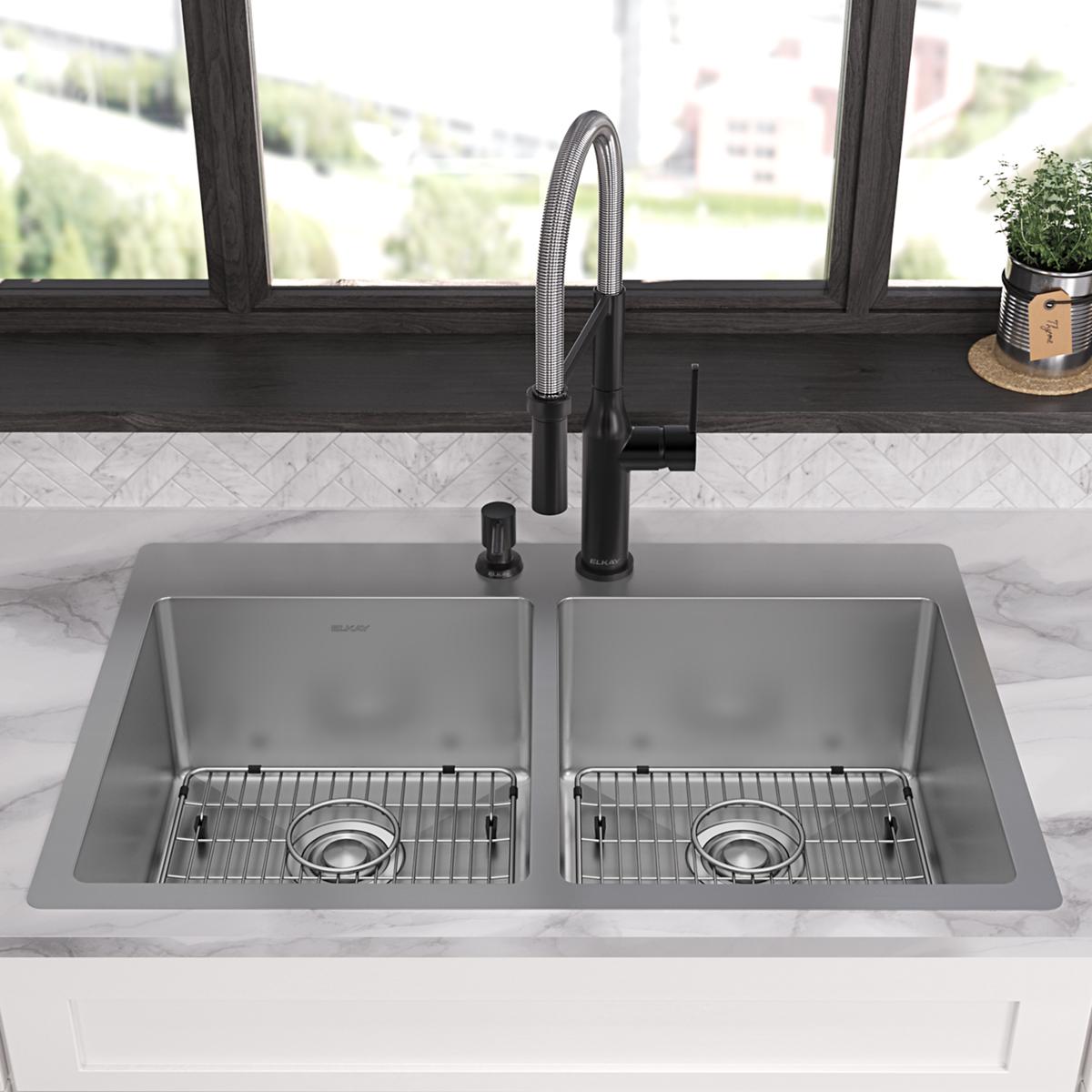Stainless steel double bowl sink with two faucet holes, black pull-down faucet, and wire basin grids installed in marble coun