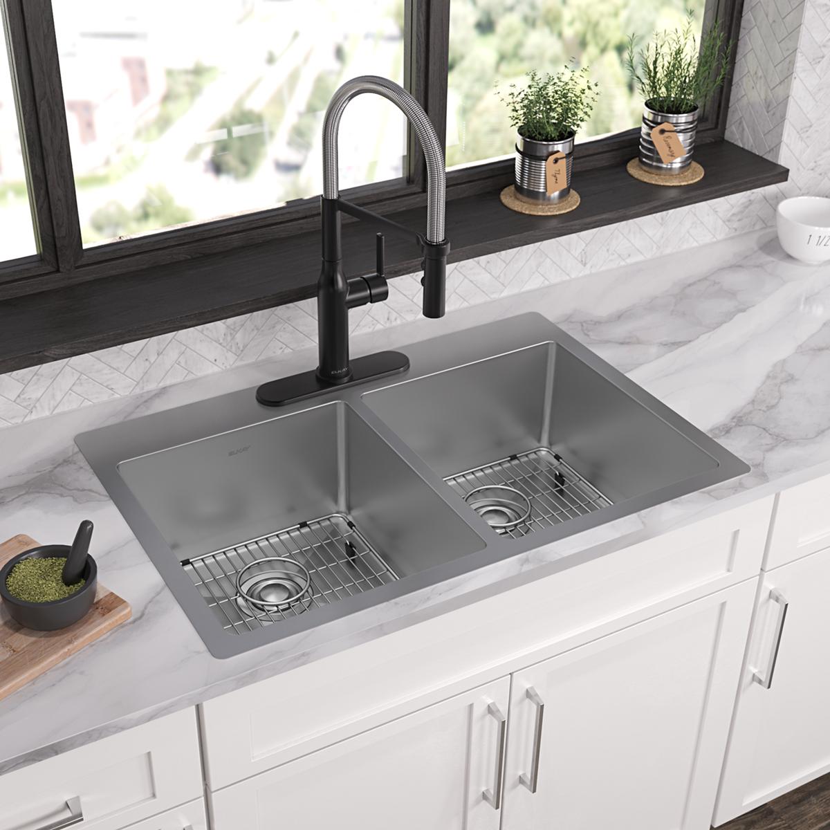 Stainless steel double bowl sink with two equal basins, grid inserts, and black pull-down faucet mounted in white kitchen cou