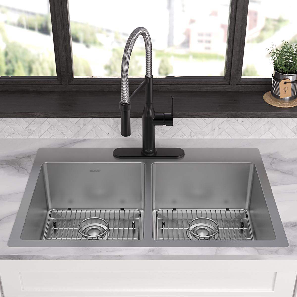 Stainless steel dual bowl drop-in kitchen sink with two equal compartments, grid inserts, and black pull-down faucet installe