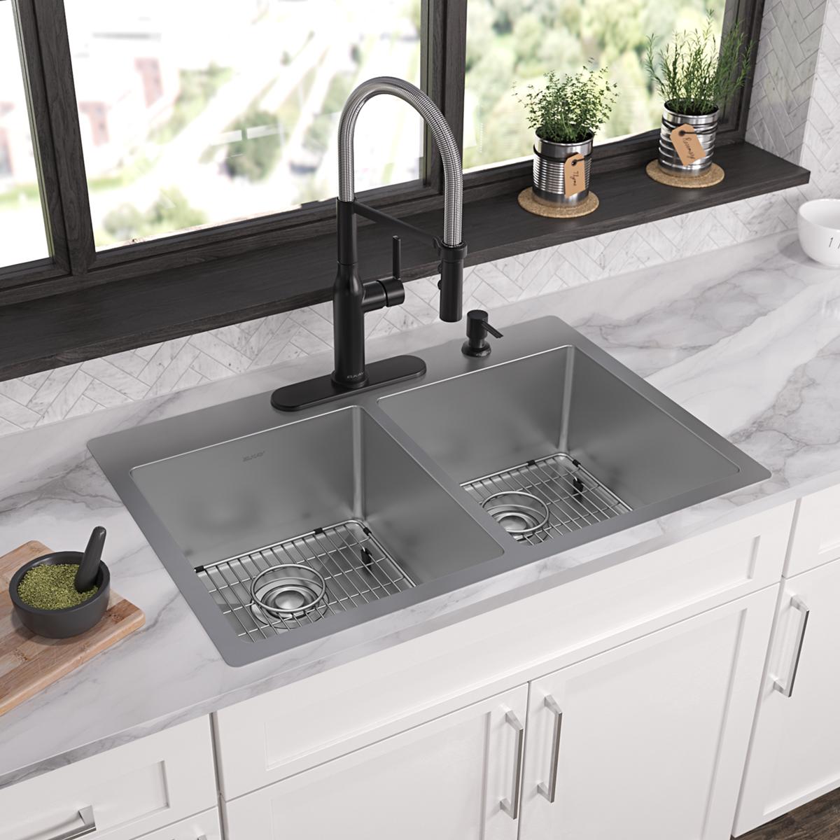 Stainless steel double bowl sink with two basin compartments, matching grids, and black pull-down faucet installed in white c