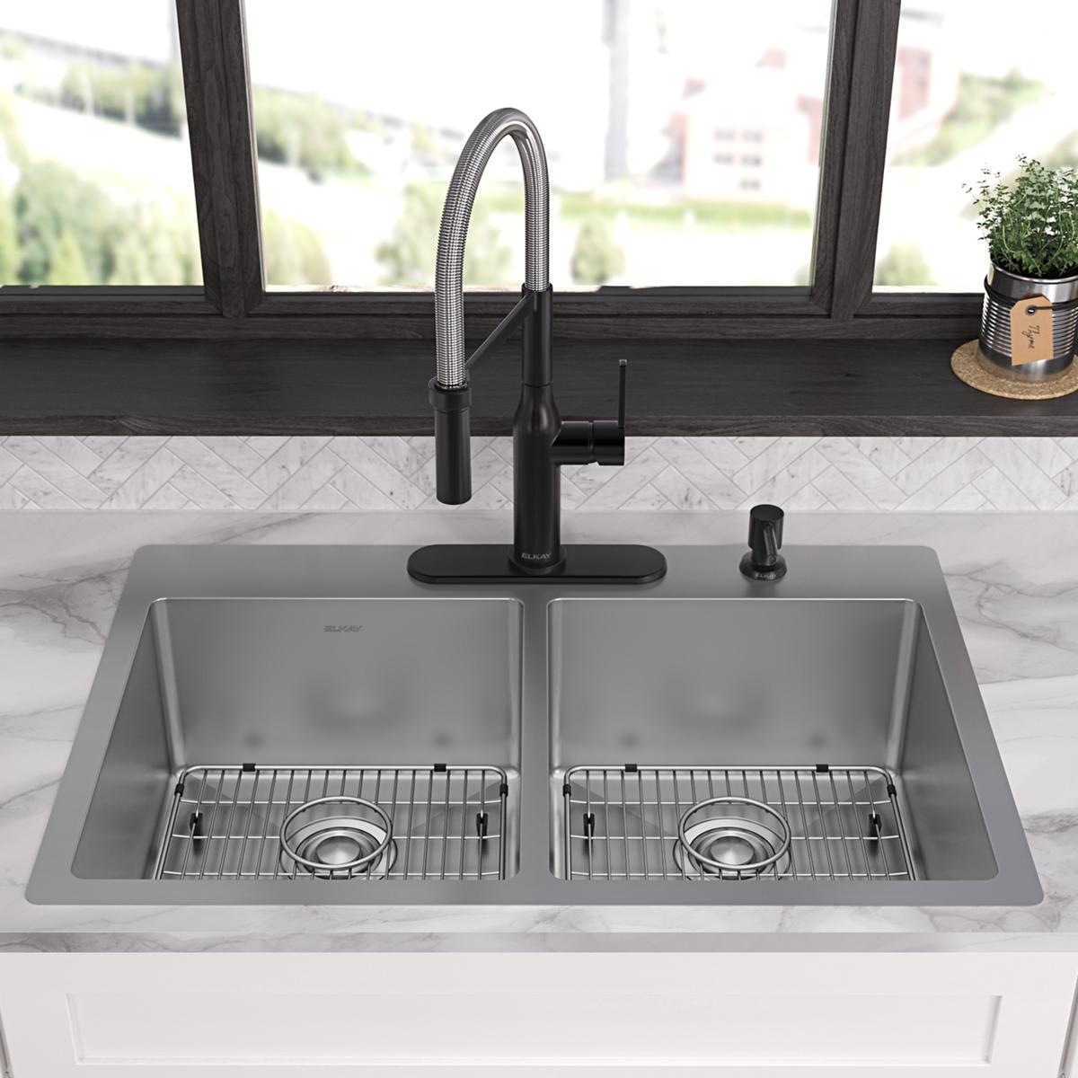 Stainless steel double bowl sink with four holes, pull-down faucet, and basin grids installed in countertop.