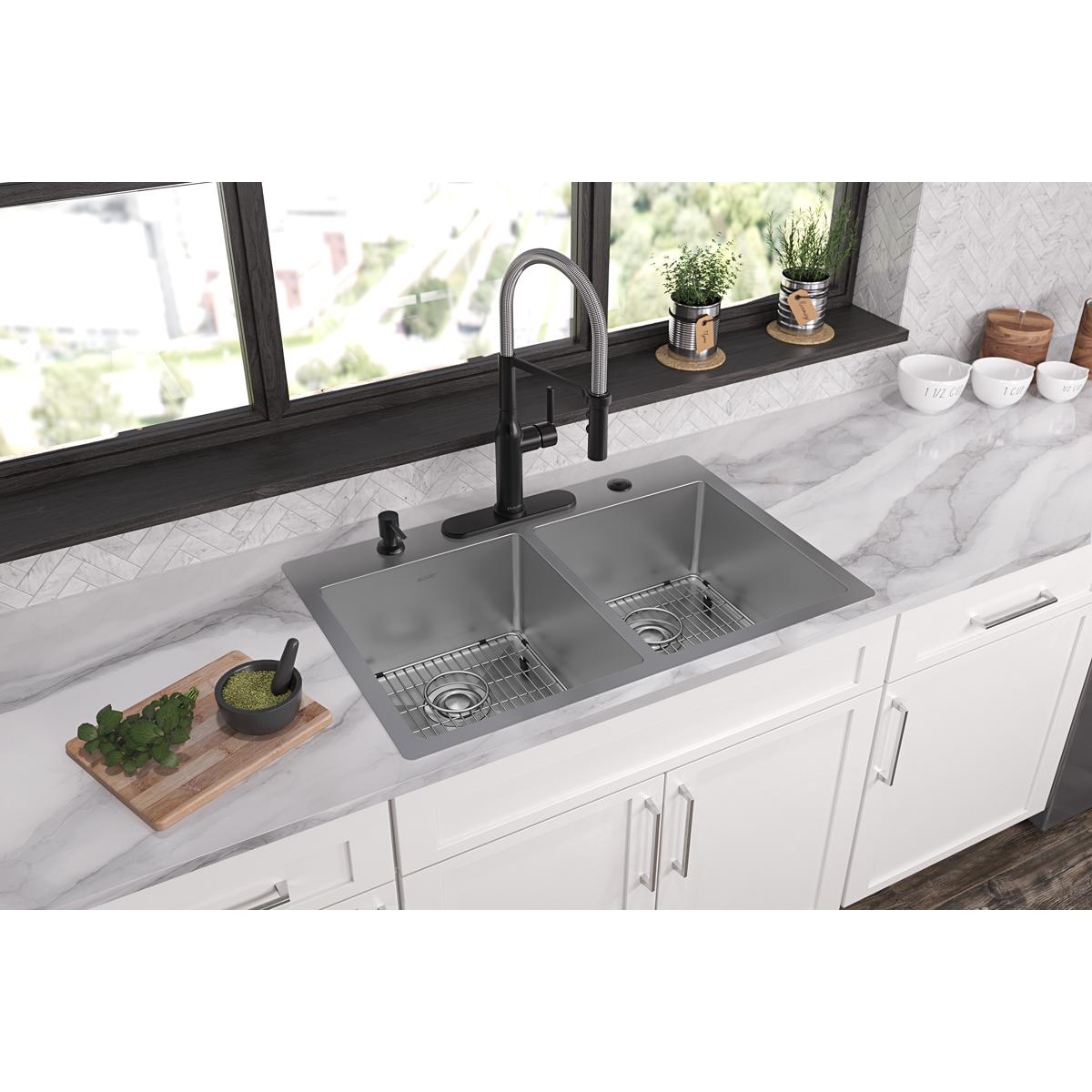 Stainless steel double bowl sink with two basin sections and drain holes installed in white kitchen countertop.