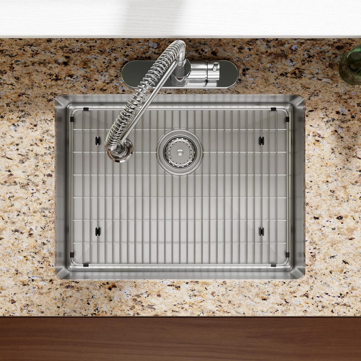 Stainless steel single bowl sink with ridged basin, drain, and flexible spray faucet mounted in speckled countertop.