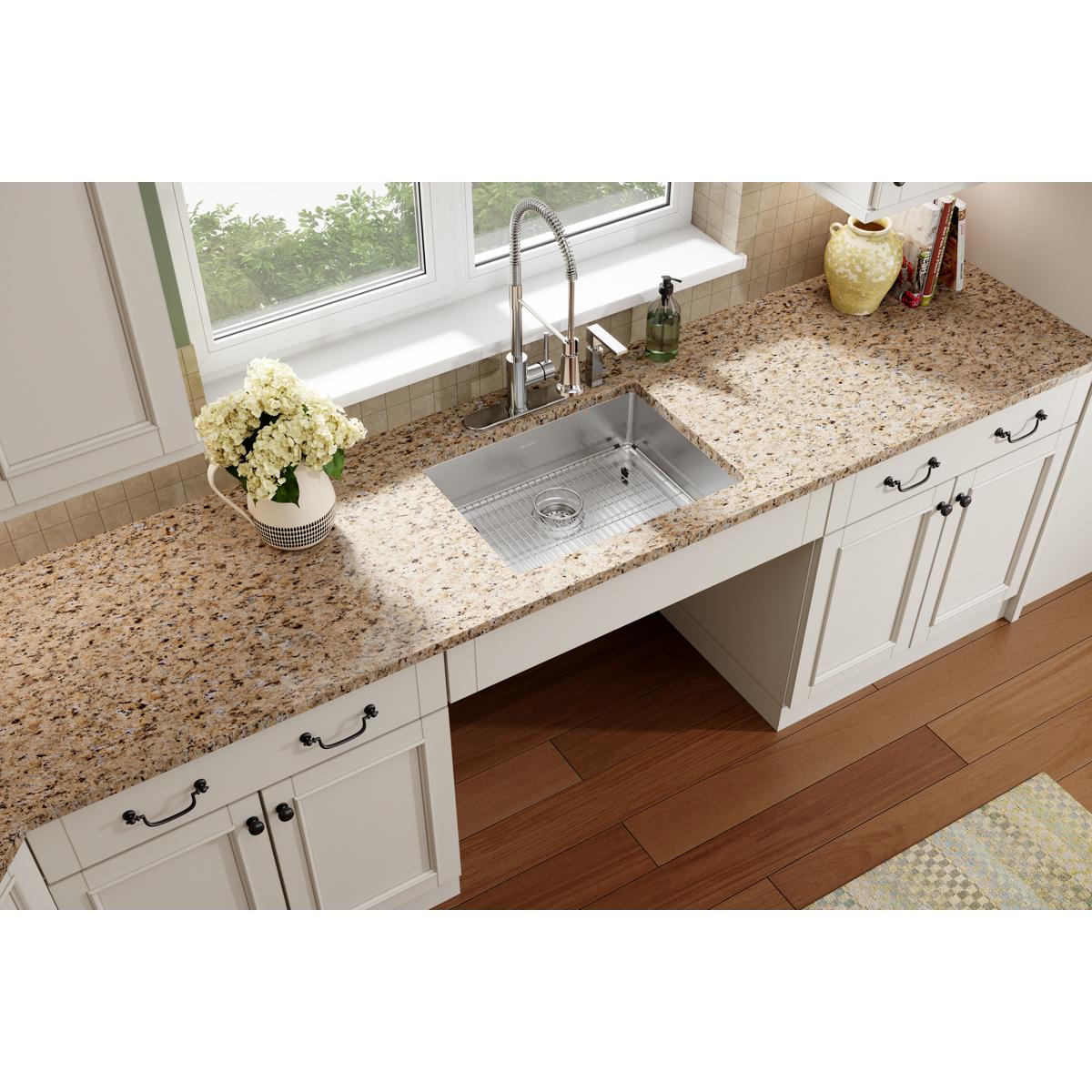 Stainless steel rectangular sink bowl installed in granite countertop with four-hole faucet mounting, grid strainer, and surr