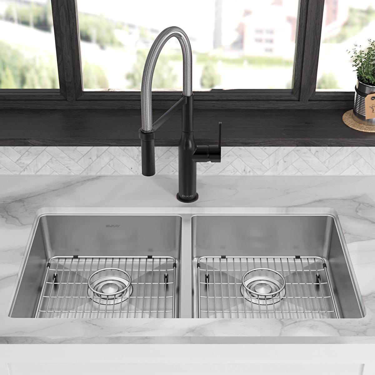 Stainless steel double bowl kitchen sink with two equal-sized basins, metal grids, and black pull-down faucet mounted on marb