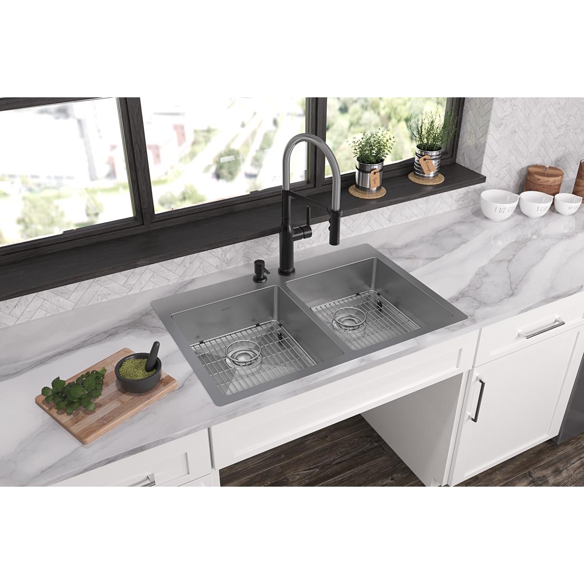 Stainless steel double bowl sink with two grid inserts installed in white cabinetry under marble countertop with black faucet