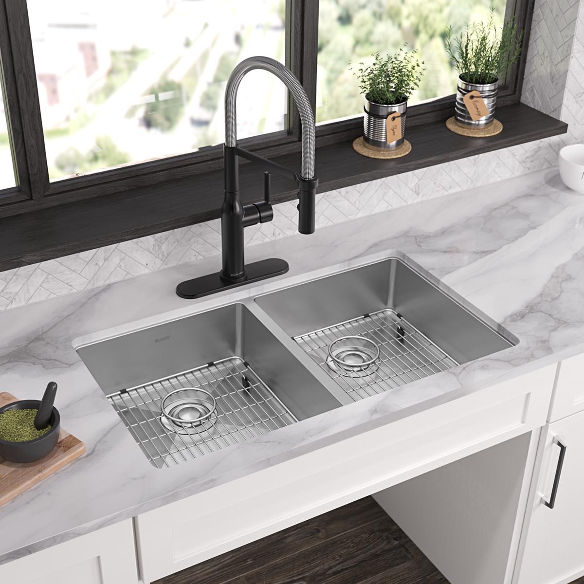 Stainless steel dual bowl sink with two wire strainers and black pull-down faucet installed in white countertop.