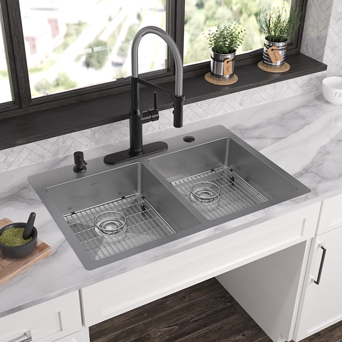 Stainless steel double bowl sink with two equal compartments, metal drain grids, and black pull-down faucet installed in whit