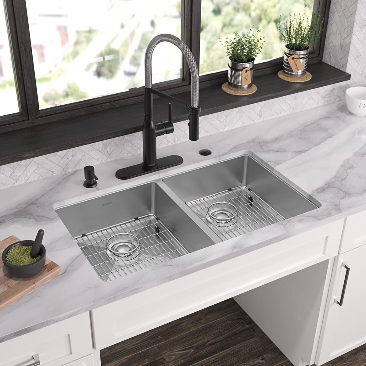 Stainless steel double bowl sink with two rectangular basins, grid inserts, and black pull-down faucet mounted on white count