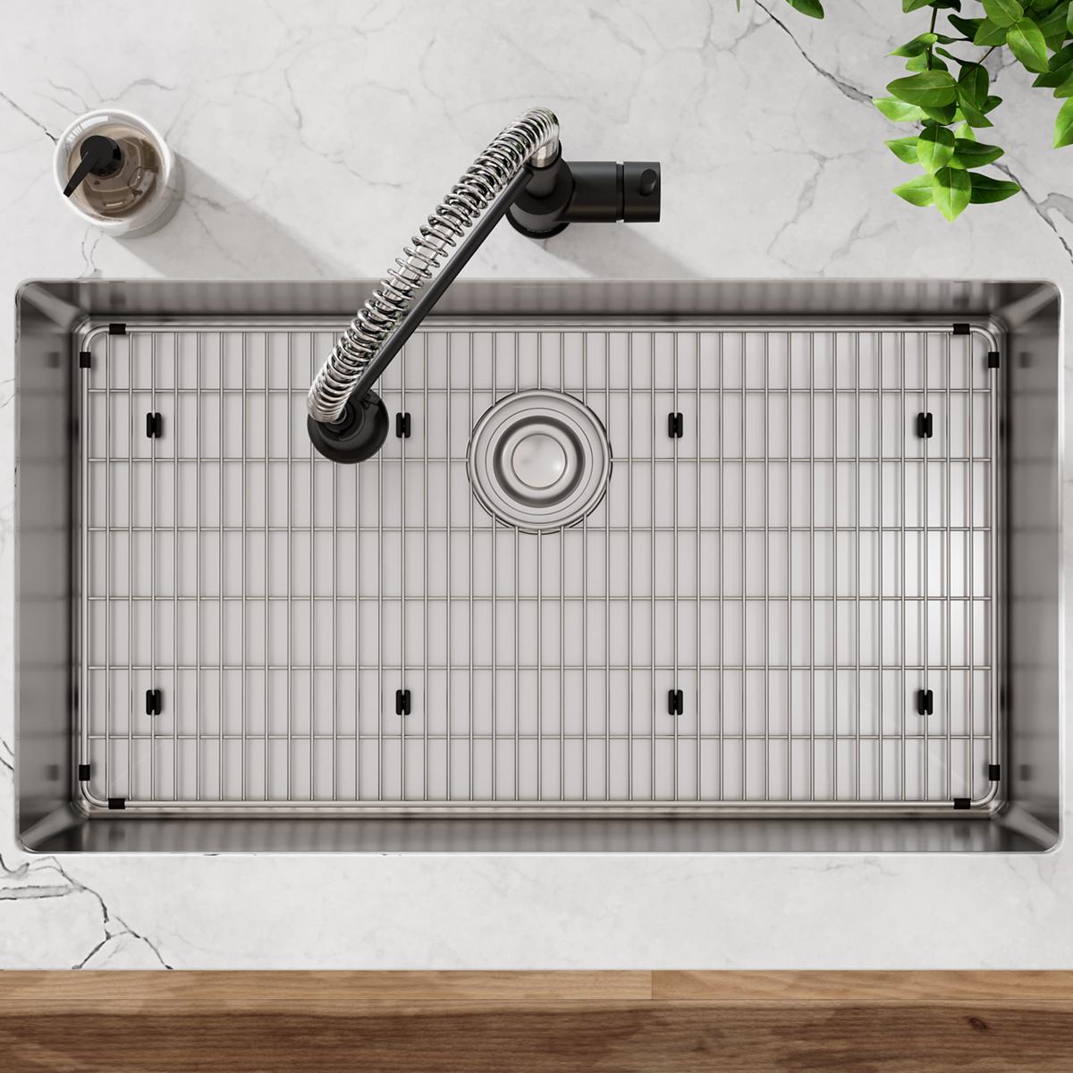Stainless steel sink grid with parallel bars and mounting feet, shown from above in sink basin.
