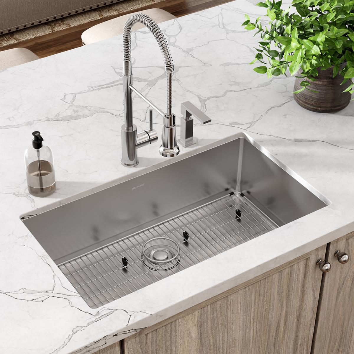 Stainless steel rectangular sink with single bowl, grid insert, and dual-mount chrome faucet with pull-down spray on marble c