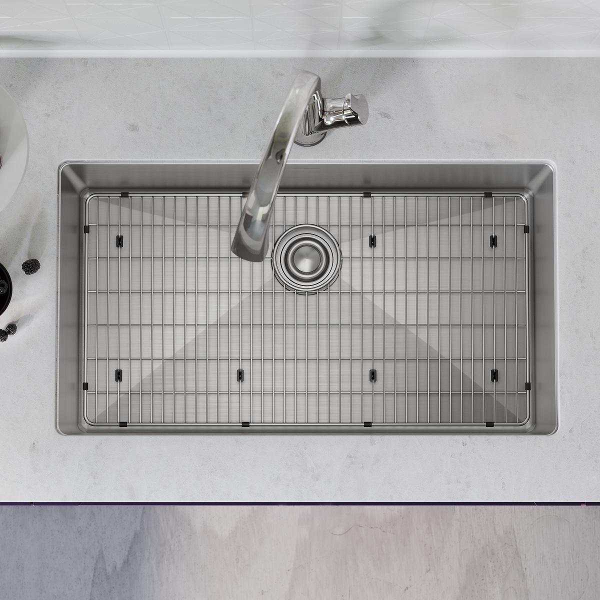 Stainless steel single bowl sink with integrated grid strainer and curved faucet mounted on marble countertop.
