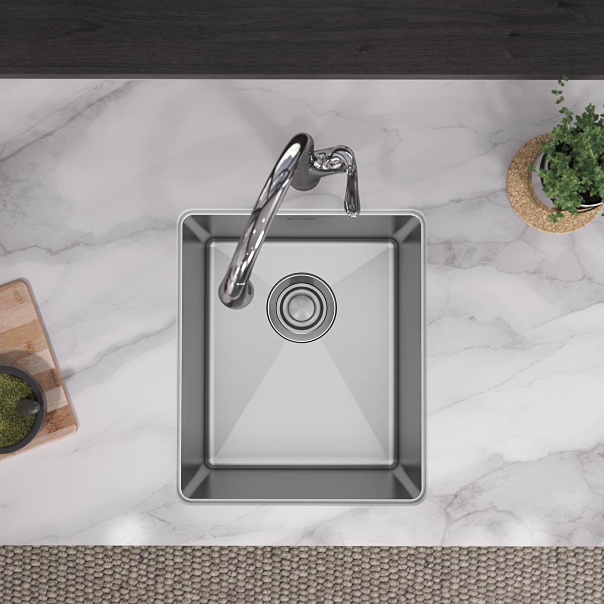 Stainless steel undermount sink with rounded single bowl and drain, installed beneath marble countertop with faucet.