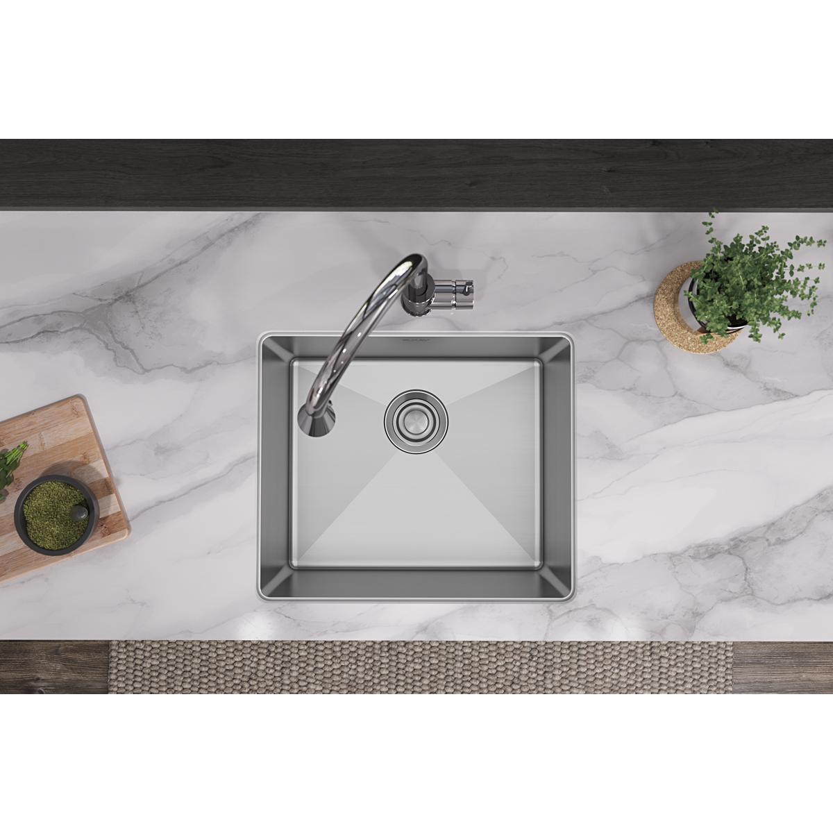Stainless steel single bowl undermount sink installed in marble countertop with chrome faucet and drain visible.