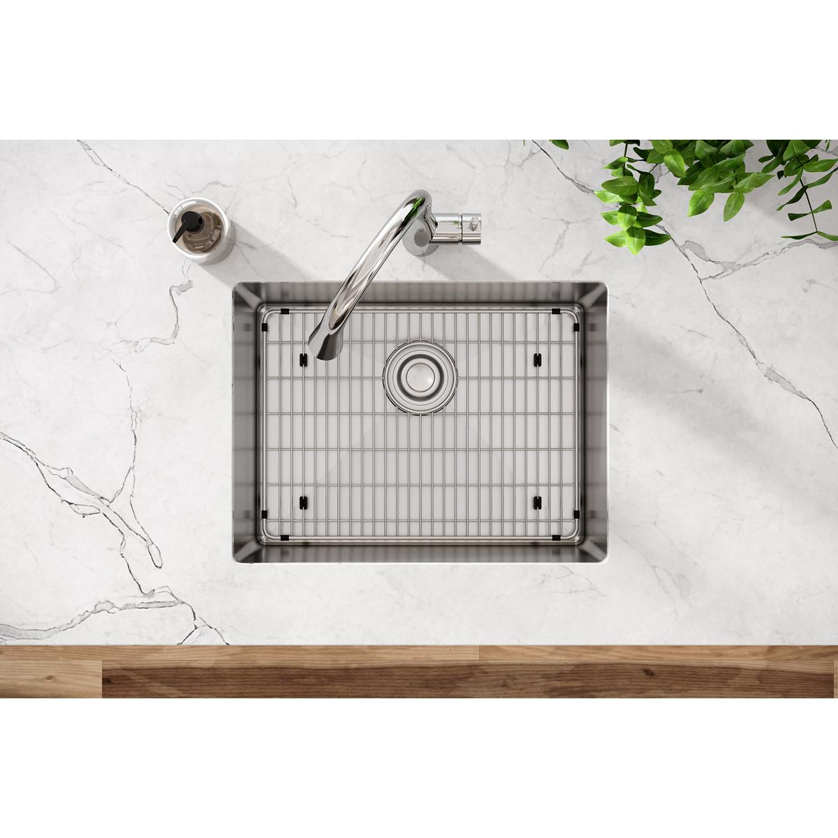 Stainless steel single bowl undermount sink with rounded corners, grid insert, and chrome faucet installed in marble countert