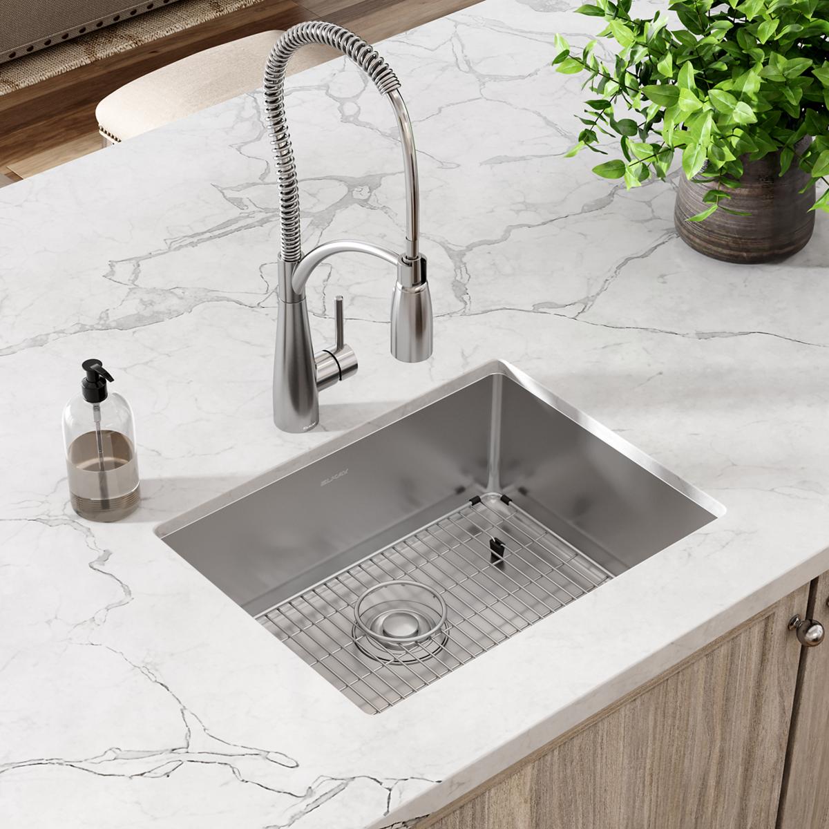 Stainless steel single bowl undermount sink with pull-down faucet and grid strainer in marble countertop.